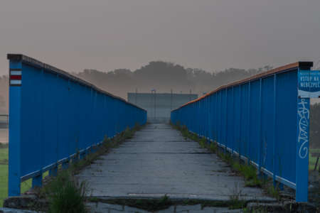 Blue bridge with fence near river Dyje with orange sunrise near Bulhary village in south fresh Moraviaの写真素材