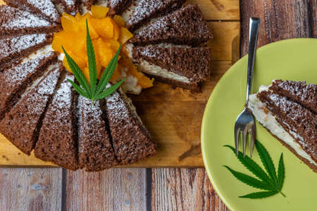 Brown cream fruit cake with apricot and marijuana butter on wooden tableの写真素材