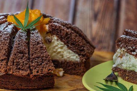 Brown cream fruit cake with apricot and marijuana butter on wooden tableの写真素材