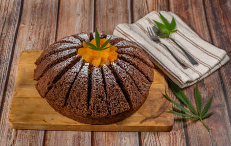 Brown cream fruit cake with apricot and marijuana butter on wooden table