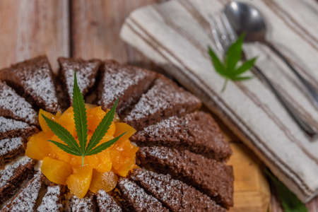 Brown cream fruit cake with apricot and marijuana butter on wooden tableの写真素材
