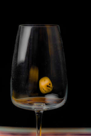 Transparent dirty glass with color dice on color wooden tableの写真素材