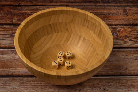 Wooden bowl brown on dark wooden table and diceの写真素材