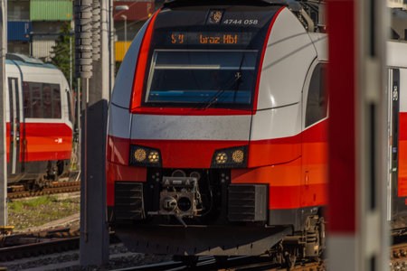 Red electric passenger train in Graz station in summer sunny fresh morning