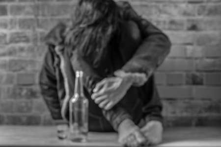 Black hair man with vodka bottle near old red brick wallの写真素材