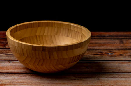 Wooden bowl with white striped dish towel on dark wooden tableの写真素材