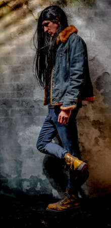 Black long hair man with jeans and big yellow shoes and old wallの写真素材