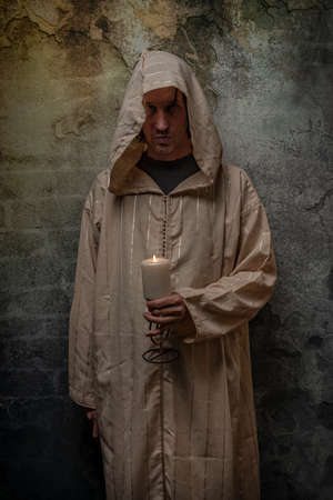 Tall man with long priest dress with stone old wallの写真素材