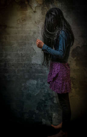 Black long hair woman in violet dress near old stone dark wall