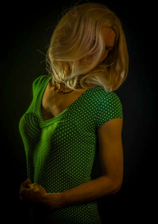 Blond hair young woman with dark green fresh backgroundの写真素材