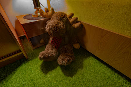 Reindeer soft toy near bed on green carpet under table dark lightの写真素材