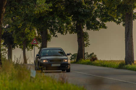 Passenger cars on alley road with leaf trees in sunset summer color eveningの写真素材