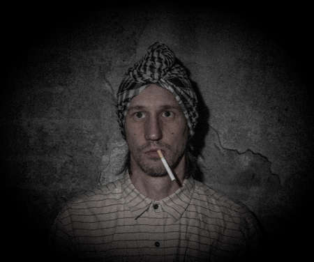 Arabian man near old stone wall with black white bandanna on headの写真素材