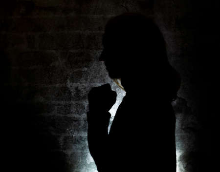 SIlhouette of blond hair woman near old stone dark wallの写真素材