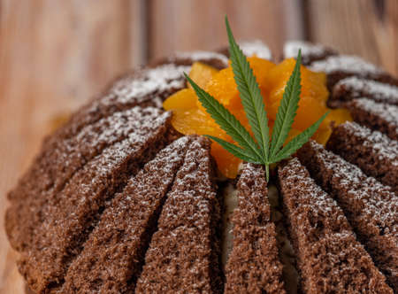 Brown cream fruit cake with apricot and marijuana butter on wooden tableの写真素材