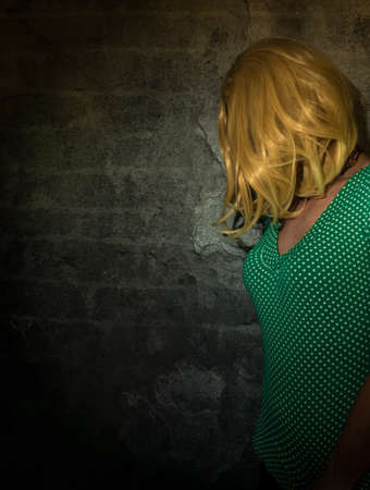 Blond hair young woman near old stone dark wall
