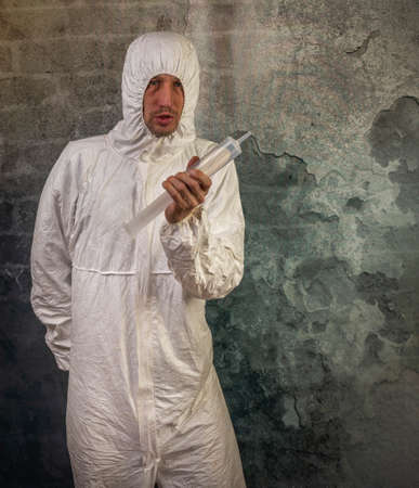 Man with white protection suit and big shot injection near old brick wallの写真素材