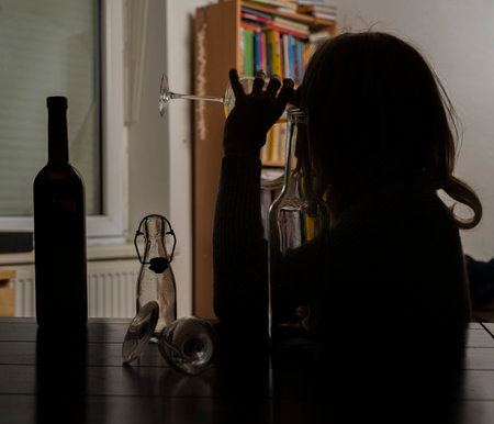 Blond hair woman with bottles of alcohol in dark interiorの写真素材