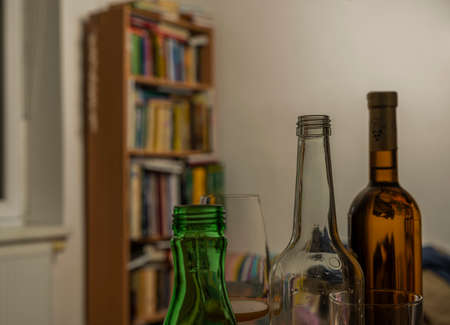 Blond hair woman under table with bottles of alcohol in dark interiorの写真素材