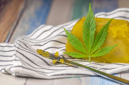Yelllow marijuana butter on color wooden table with clean striped tea towelの写真素材