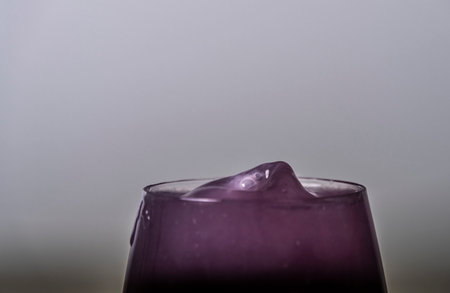 Color drops fall to wine glass with color light liquidの写真素材