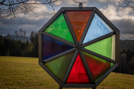 Color glass oval near green meadow and forest in Austria winter countryside