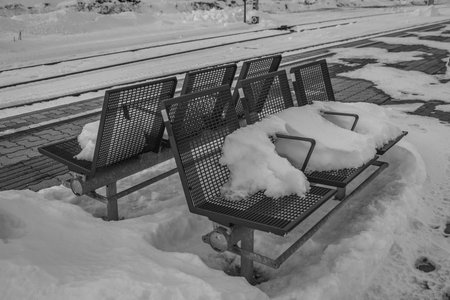 Winter evening in Spital am Pyhrn in Austria with snowy and frosted benches on platformの写真素材
