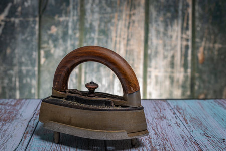 Old metal iron on old wooden blue table with old wooden wall backgroundの写真素材