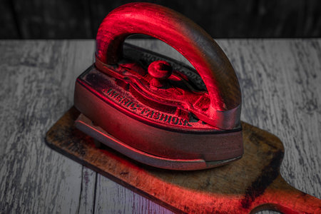 Old metal iron on old wooden blue table with dirty chopping boardの写真素材