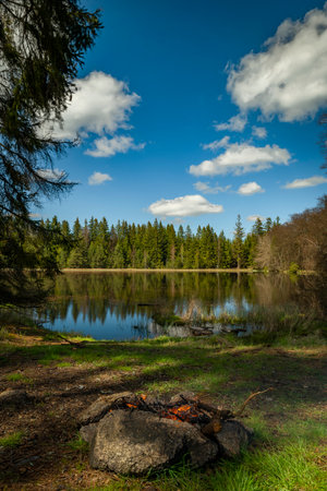 Fireplace near blue water pond in spring light green forest in Slavkovsky forest mountainsの写真素材