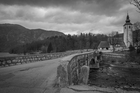 Dark cloudy sunny evening with no colors near Bohinj lake with old stone bridgeの写真素材