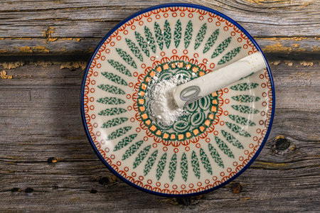 Small plate on old wooden color table with white powder of cocaine with paper bank noteの写真素材