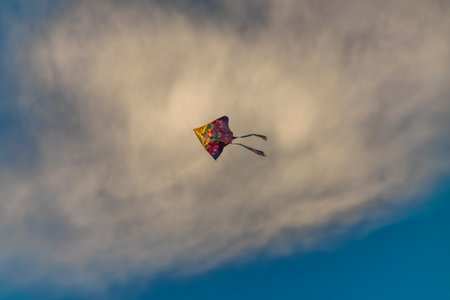 Color kite with blue sky and white clouds in sunny nice autumn windy eveningの写真素材