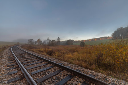 Railway track for passenger trains in autumn foggy cold morningの写真素材