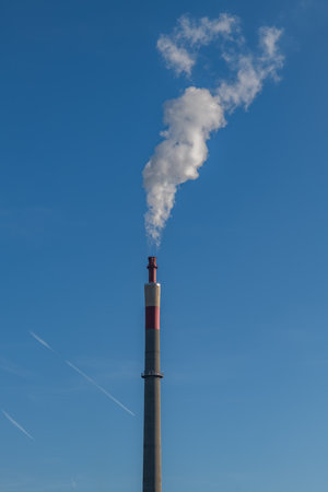 Blue autumn cold sky with chemical factory chimney with white smokeの写真素材