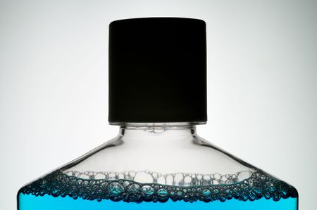 Blue mouth wash illuminated from behind showing glowing liquid and dark bottle outline. May be perfume, essence, etc.の写真素材