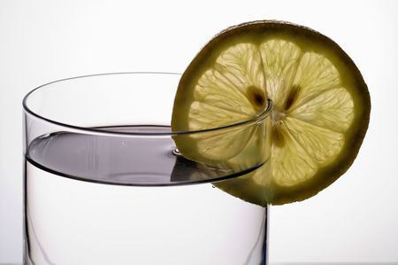 Glass of water (or liquor) with lemon slice closeupの写真素材