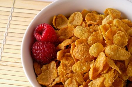 Cereal bowl with raspberries closeup on bamboo mat
