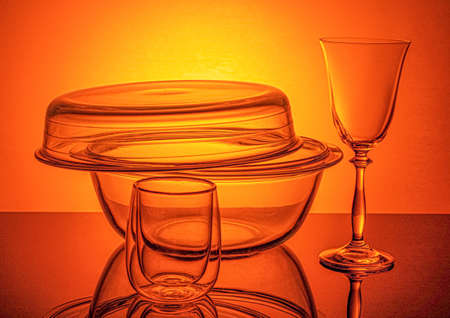 a glass heat-resistant saucepan and a wine glass on an orange backgroundの写真素材