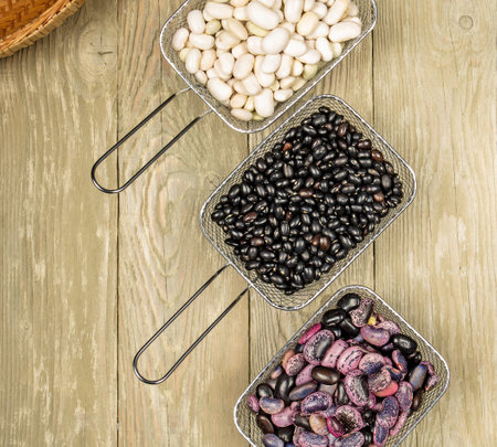Three metal baskets with colorful beans on a wooden background