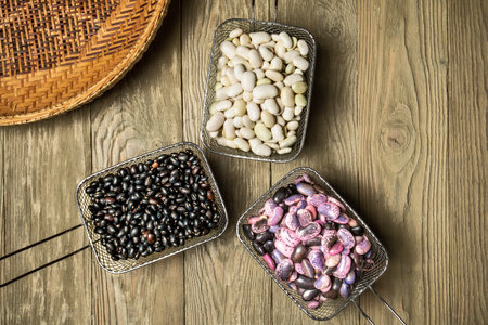 Three metal baskets with colorful beans on a rough wooden tableの写真素材