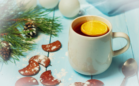 Christmas still life, a mug of hot tea with lemon on a blue wooden table surrounded by Christmas accessoriesの写真素材