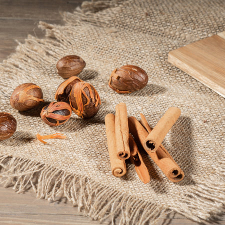 On a coarse burlap napkin lies a bunch of cinnamon and nutmeg. village scene