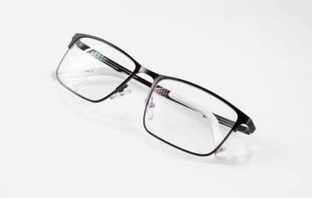 Glasses in a black metal frame are reflected in a white mirror background and have glare on the lensesの写真素材