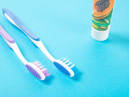 Daugavpils, Latvia April 1, 2023. Two multi-colored plastic toothbrushes and a tube toothpaste on a blue backgroundの写真素材