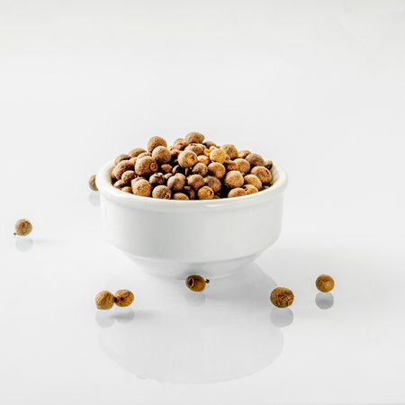 A white ceramic cup filled with black pepper is reflected in a white mirror stand.の写真素材