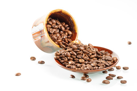 Coffee beans are scattered from a coffee cup on a saucerの写真素材