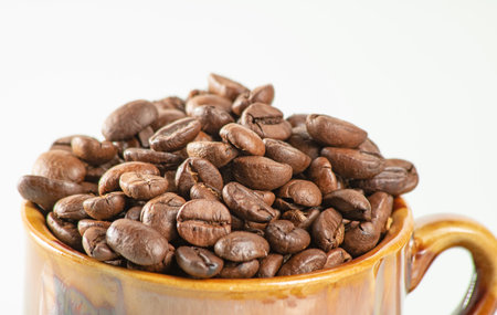 coffee theme. Ceramic cup filled to the brim with coffee beans on a white background.Close upの写真素材
