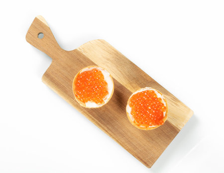 Two tartlets filled with red salmon caviar on a wooden kitchen board, top viewの写真素材