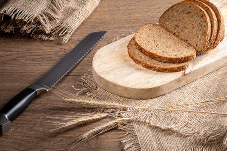 Rye bread, knife, ears of barley on a burlap napkin on the kitchen table.Rustic style